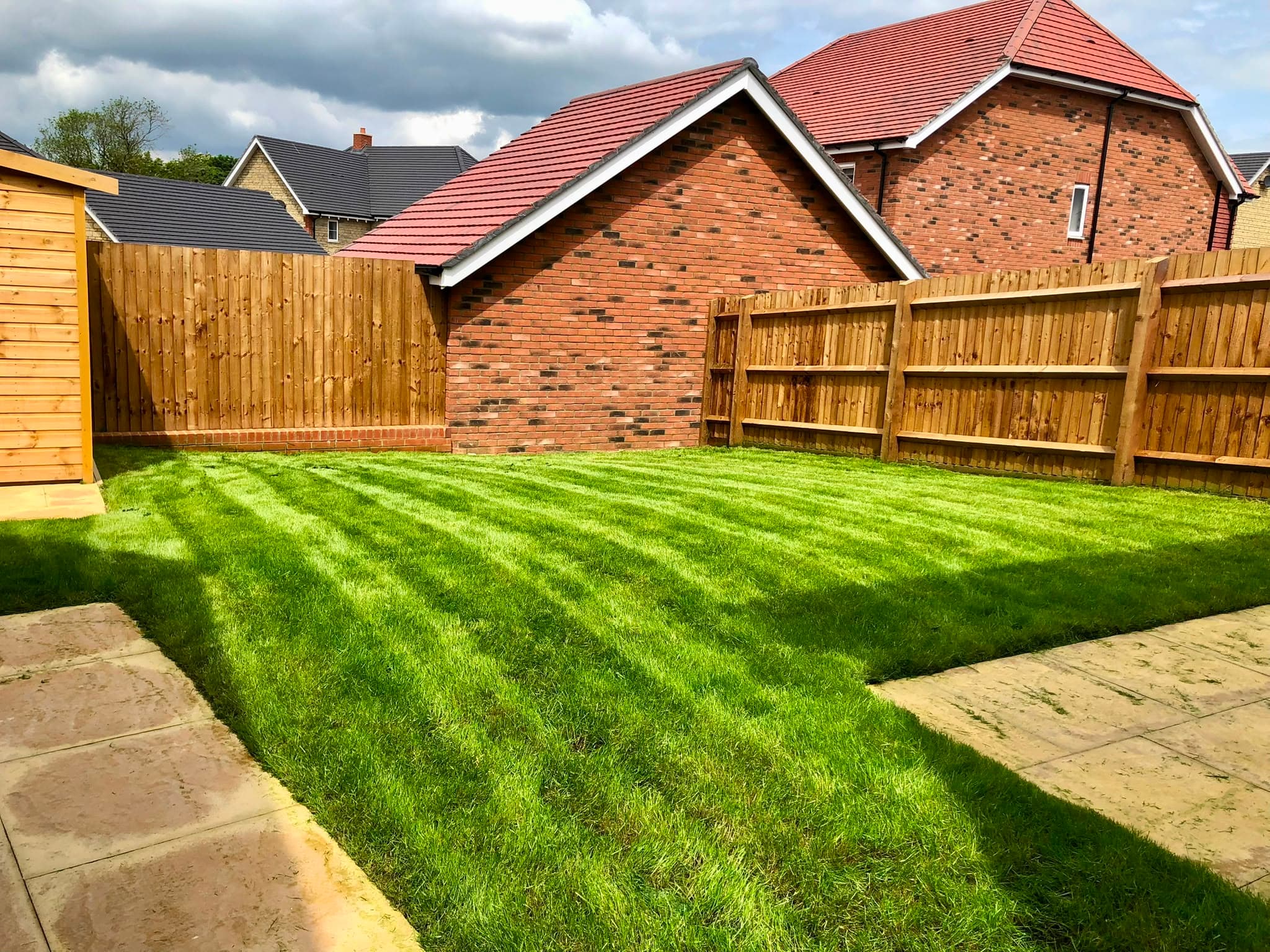 A freshly cut back lawn with clean mower stripes, edged up to new fencing and a paved patio